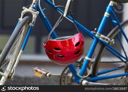 Closeup image of used red bicycle helmet with home in background