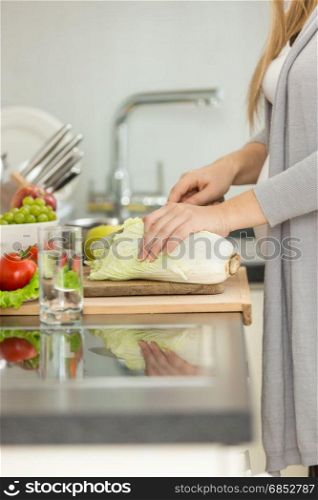 Closeup image of woman cutting fresh cabbage for soup