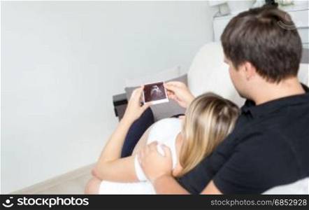 Closeup image of young couple expecting baby holding ultrasound image of fetus