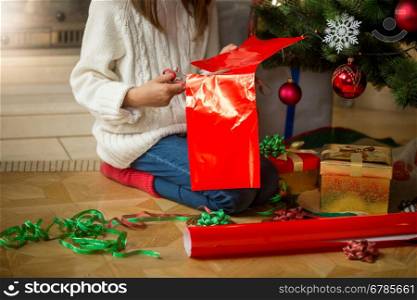 Closeup image of young girl wrapping presents under Christmas tree