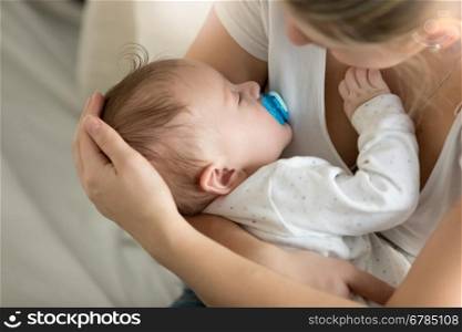 Closeup image of young mother with her sleeping baby at bedroom