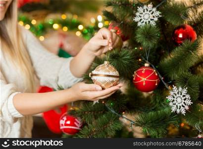 Closeup image of young woman holding golden Christmas bauble in hands