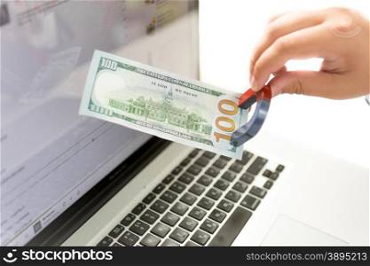 Closeup isolated money of man pulling money from laptop with magnet