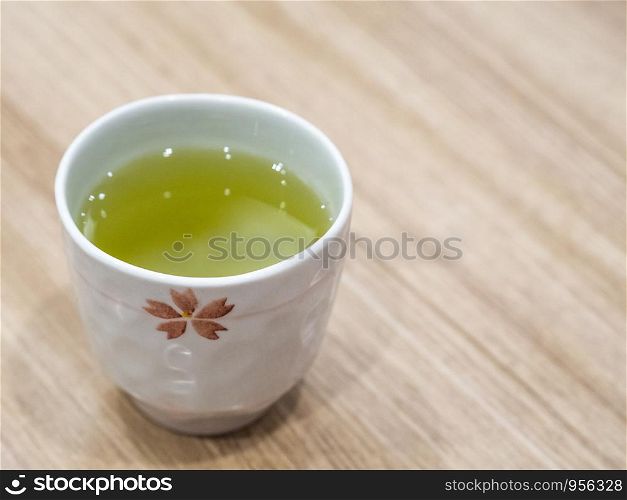 Closeup Japanese style cup of hot green tea on wooden table in the restaurant.