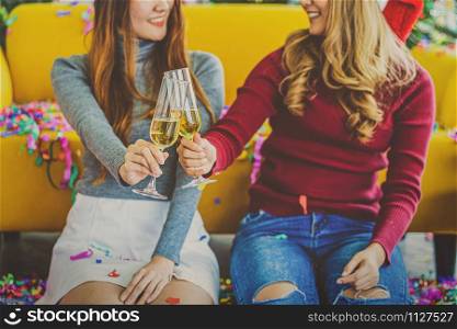 Closeup LGBTQ couple asian happiness women wearing colorful red sweaters holding and cheering prosecco in christmas party with xmas trees, asian or asean indoor house, xmas and new year concept