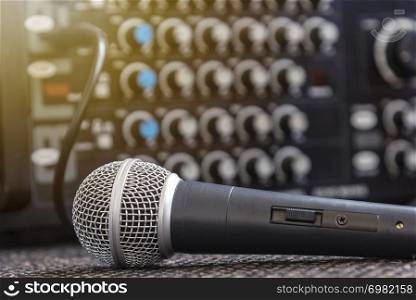 Closeup microphone with blurred sound mixer background.