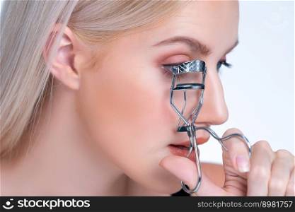 Closeup natural soft facial makeup beautiful personable woman with perfect smooth cosmetic clean skin correct eyelash curler with metal mechanic beauty accessory in isolated background.. Closeup personable woman correct eyelash curler with alluring facial makeup