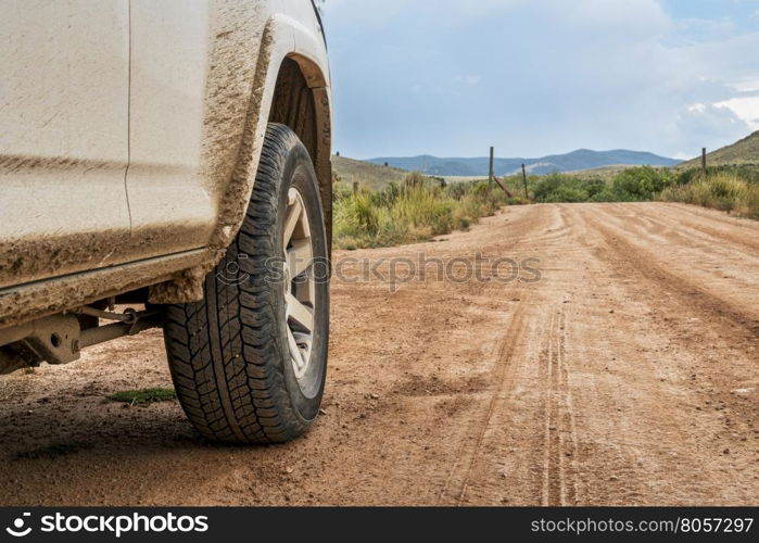 Closeup of 4x4 SUV car driving on a dusty dirt road