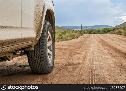 Closeup of 4x4 SUV car driving on a dusty dirt road