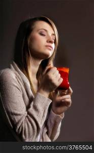 Closeup of a beautiful caucasian woman holding a nice red cup of warm beverage gray background