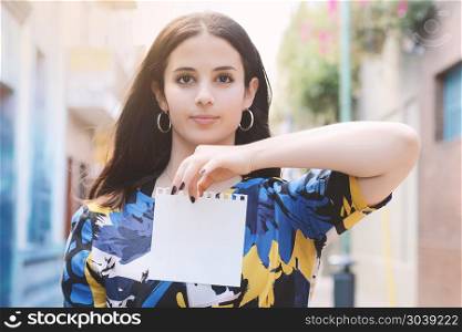 Closeup of a beautiful woman showing a blank notepad. Outdoors. Closeup of a beautiful woman showing a blank notepad.