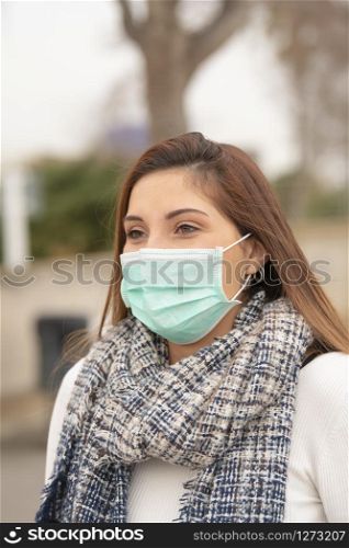 Closeup of a beautiful woman wearing a green surgical mask to prevent an infection. Disease prevention concept.. woman wearing a surgical mask for prevention