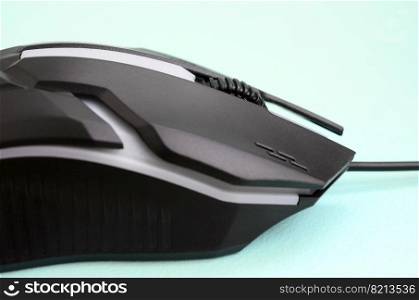 Closeup of a black gaming optical mouse on a blue background. Device for cybersport and online video games. Closeup of a black gaming optical mouse on a blue background