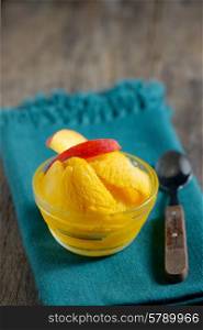 Closeup of a bowl of mango sorbet on old table