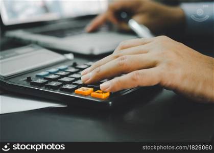 Closeup of a businessman&rsquo;s hand and a calculator. Business, Finance, Investment, Tax and Concept Economy. Closeup of a businessman&rsquo;s hand and a calculator.