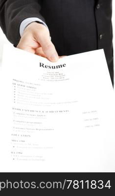 Closeup of a businessman&rsquo;s hand holding out a resume. Focus on the hand and the word Resume.