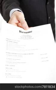 Closeup of a businessman&rsquo;s hand holding out a resume. Focus on the hand and the word Resume.