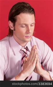 Closeup of a businessman with hands clasped and eyes closed in prayer posture