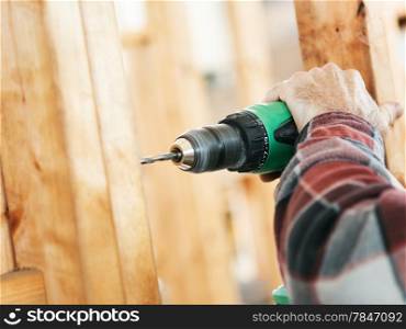 Closeup of a carpenter&rsquo;s hands using a drill on a construction site. Focus on drill and hand. Shallow depth of field.