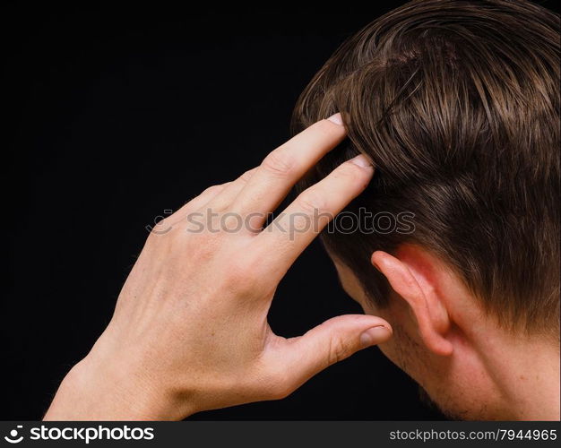 Closeup of a caucasian male thinking with one hand towards head isolated on black