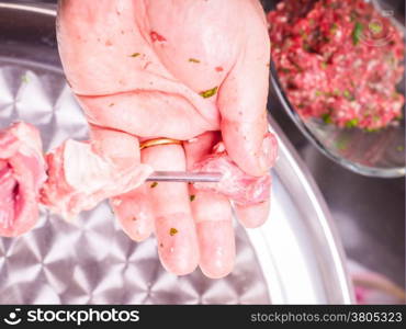 Closeup of a chef entering pieces of meat onto a skewer, making shish kebab