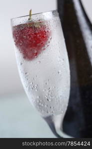 Closeup of a chilled glass of champagne with a strawberry floating in it