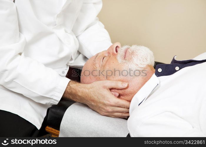 Closeup of a chiropractor adjusting a senior patient&rsquo;s cervical spine (neck).