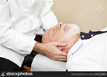 Closeup of a chiropractor adjusting a senior patient&rsquo;s cervical spine (neck).