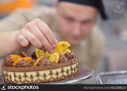 Closeup of a concentrated male pastry chef decorating dessert cake food in the kitchen