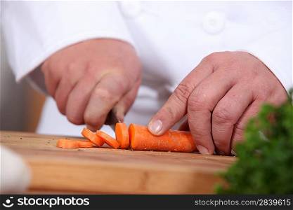 closeup of a cook cutting carrots