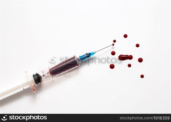 Closeup of a disposable syringe and many blood drops isolated on white close-up. Closeup of a disposable syringe and many blood drops isolated on white