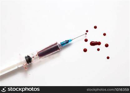 Closeup of a disposable syringe and many blood drops isolated on white close-up. Closeup of a disposable syringe and many blood drops isolated on white