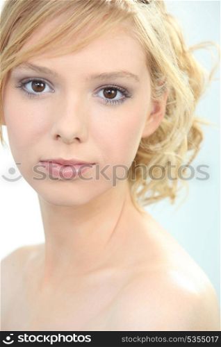 Closeup of a fair haired young woman wearing makeup but no clothes.