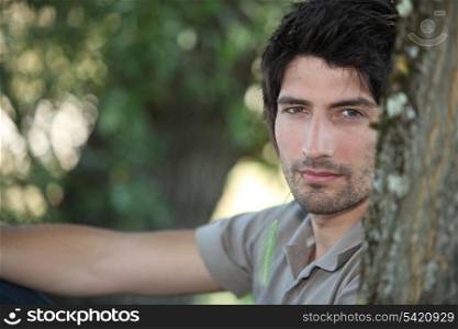 Closeup of a handsome young man sitting amongst the trees