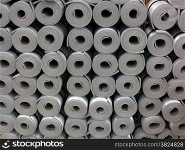 Closeup of a lot of rolled up gray foam sleep mats camping beds or fitness yoga equipment as background. Travel and sport.