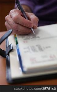 Closeup of a male hand writing in a personal organizer