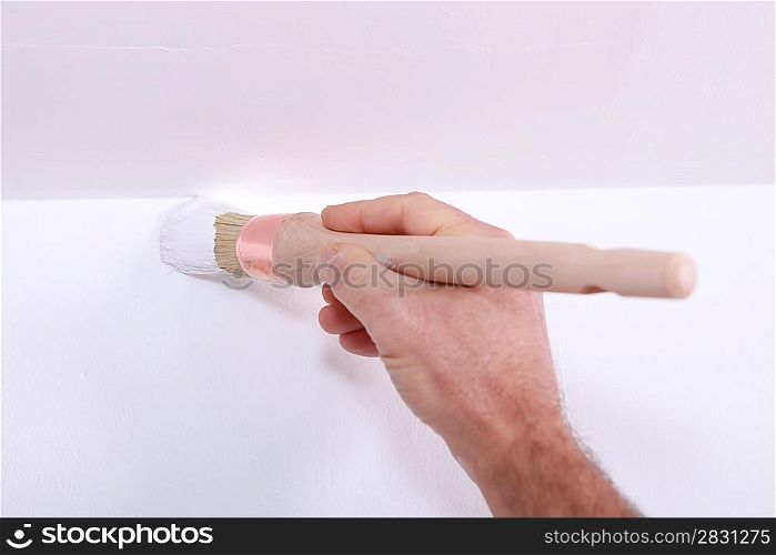 Closeup of a man cutting in a corner with white paint