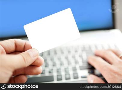 Closeup of a man shopping online using laptop with credit card. Credit card is blank. Credit card template