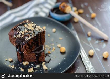 Closeup of a plate of fresh homemade brownies with hazelnuts on a striped napkin and wooden table.