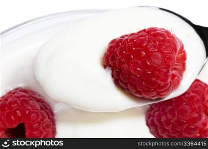 closeup of a raspberry on a spoon with yogurt. closeup of a raspberry on a spoon with yogurt top of other raspberries in a dessert