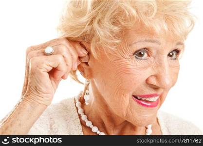 Closeup of a senior woman inserting a hearing aid in her hear. Focus on the hearing aid.