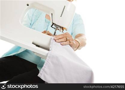 Closeup of a senior womans hands as she uses a sewing machine.