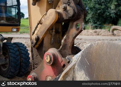 closeup of a shovel with excavator in the background