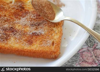 closeup of a slice of buttered toast with cinnamon sugar sprinkled over. Cinnamon toast with spoon