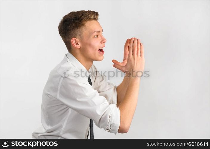 Closeup of a teenager screaming. Teenager is screaming loudly with hands near his face.