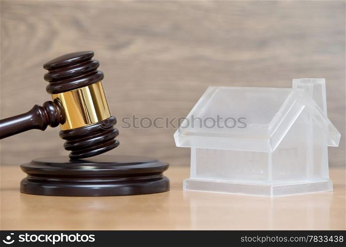 Closeup of a toy house model and a brown gavel