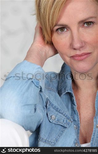 Closeup of a woman in her late thirties wearing a denim shirt