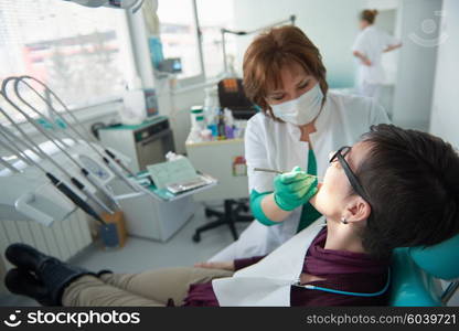 Closeup of a woman patient at the dentist waiting to be checked up with the woman doctor in the background