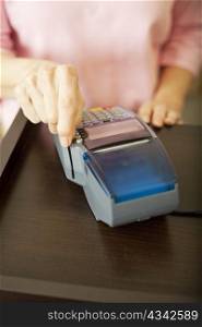 Closeup of a woman&rsquo;s had swiping a debit card through a scanner. Shallow depth of field.