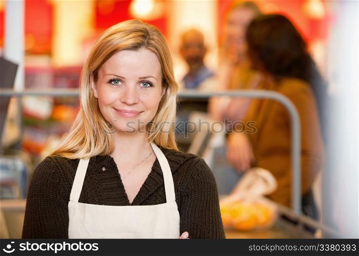 Closeup of a young shop assistant with customer in the background